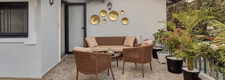 Outdoor seating area with chairs around a table and potted plants towards the side at Lime Tree Villa with Private Pool | Luxury Stay in Goa.